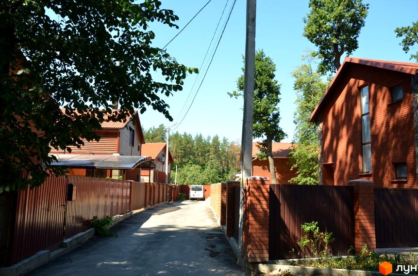 Будинок з червоної цегли та дерев'яними елементами на вулиці Давидчука (Комінтерна). Навколо будинку паркан та зелені насадження.