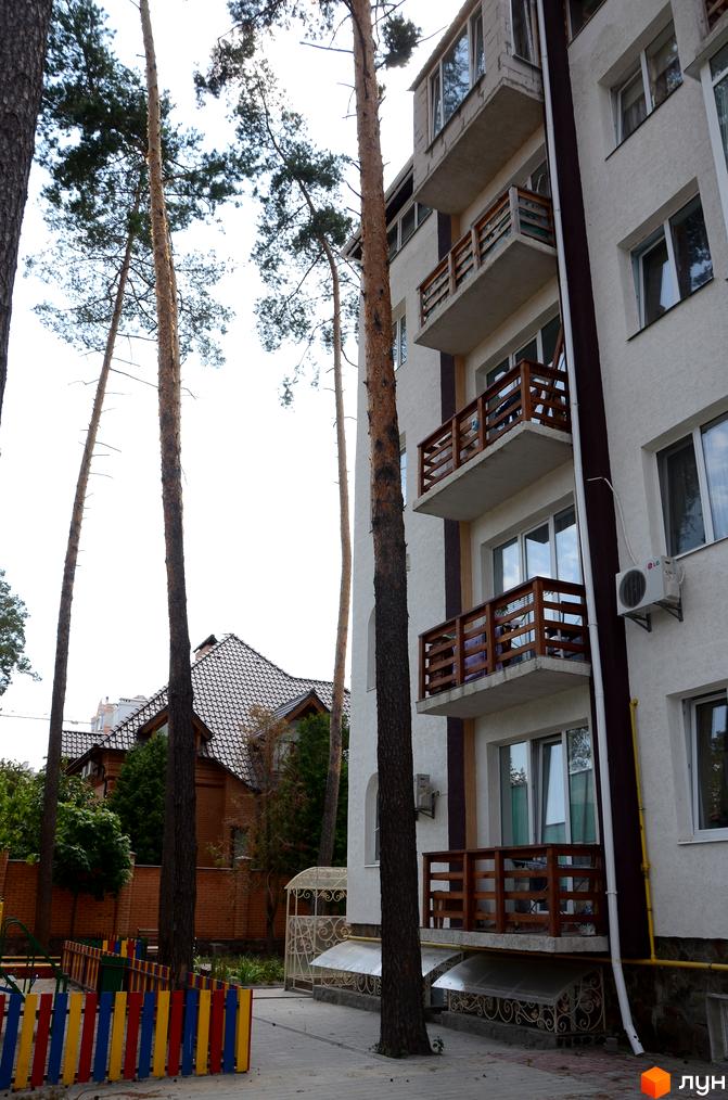 Зовнішній вигляд новобудови ЖК Затишний на вул. Університетській з балконами та вікнами. Прибудинкова територія з дитячим майданчиком та зеленими насадженнями.