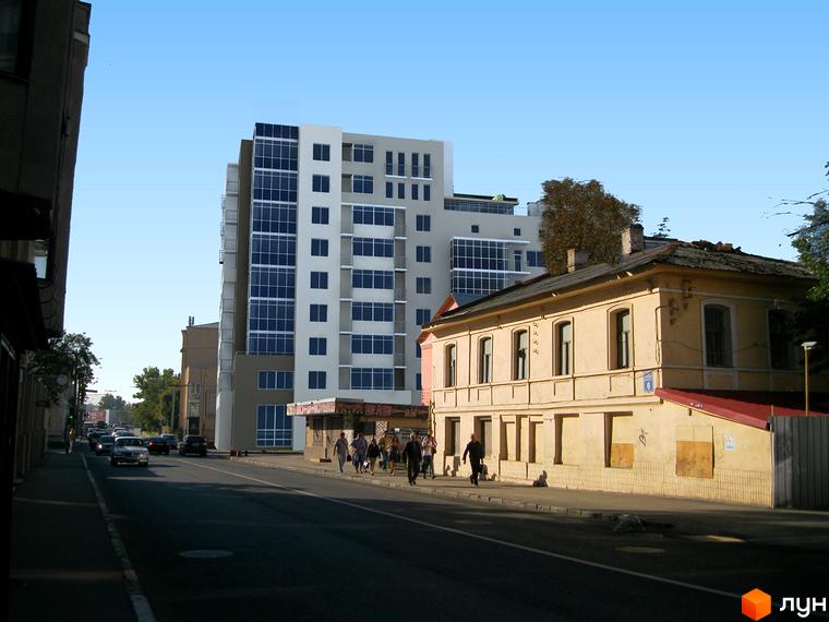 Новобудова Подільський з фасадом з вікон та балконів. Поруч розташована стара будівля та вулиця з автомобілями.