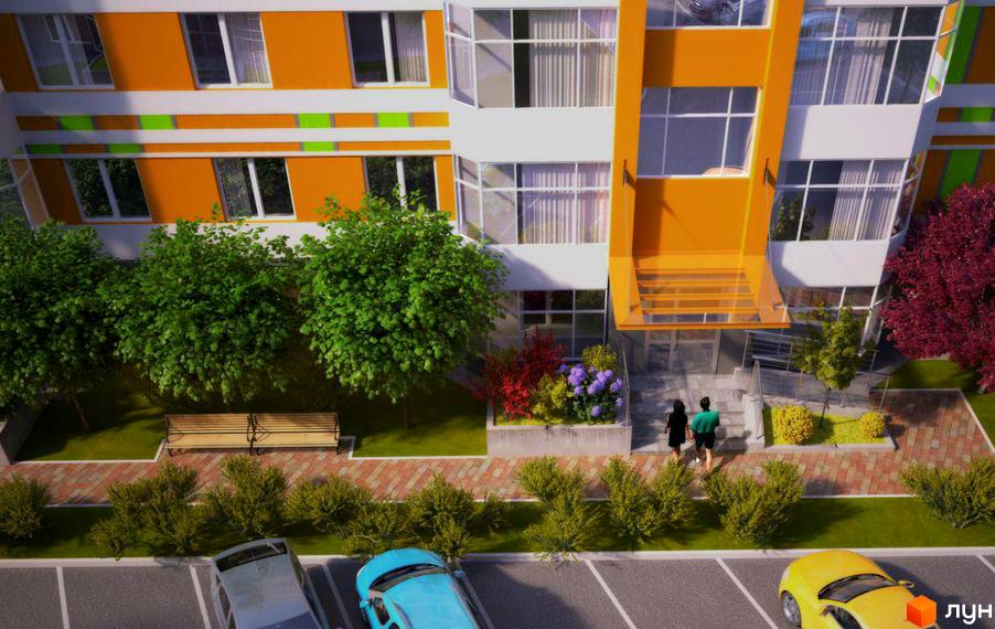 Зовнішній вигляд будинку ЖК Позитив з оранжевими та білими фасадами, скляними балконами та зеленими деревами на прибудинковій території. На фото також видно лавку та парковку з автомобілями.