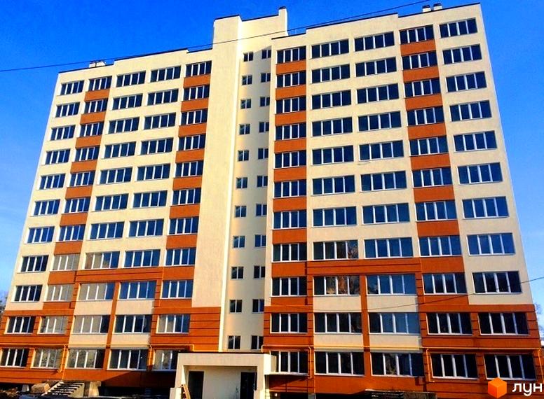 Зовнішній вигляд новобудови ЖК Затишна Оселя з численними вікнами та балконами. Будинок має світлий фасад з помаранчевими вставками.