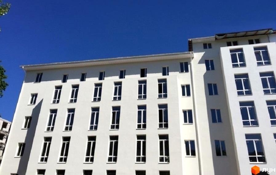 Зовнішній вигляд будинку на вулиці Біблика (Другої П'ятирічки), 4. Багатоповерхова будівля з великими вікнами на фоні синього неба.