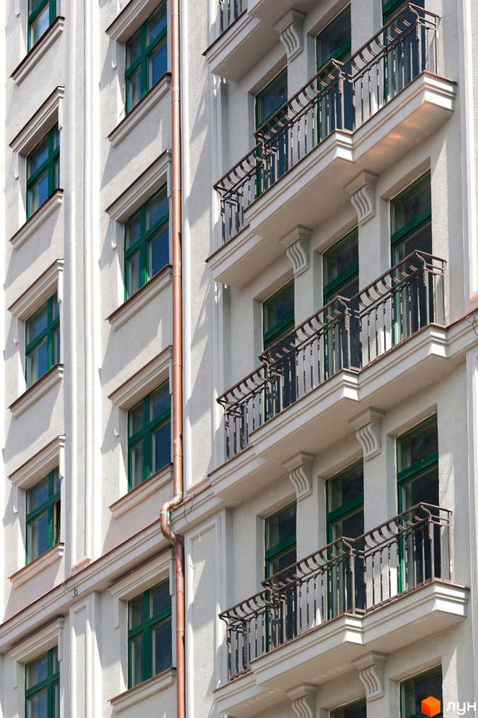 Фасад житлового комплексу Зелена тераса з балконами та зеленими вікнами. Зовнішній вигляд будівлі з елементами декору.