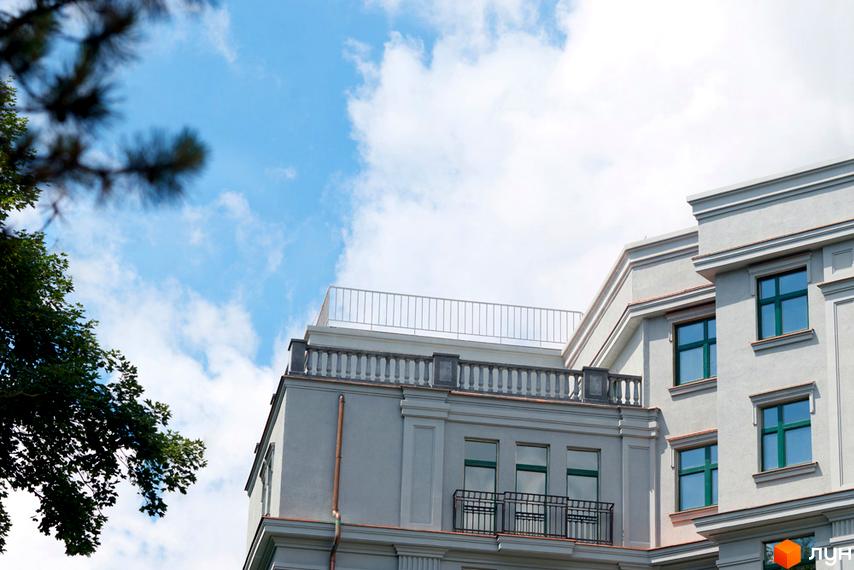 Житловий комплекс Зелена тераса. Сучасна архітектура будинку з балконами та вікнами на тлі блакитного неба з хмарами.