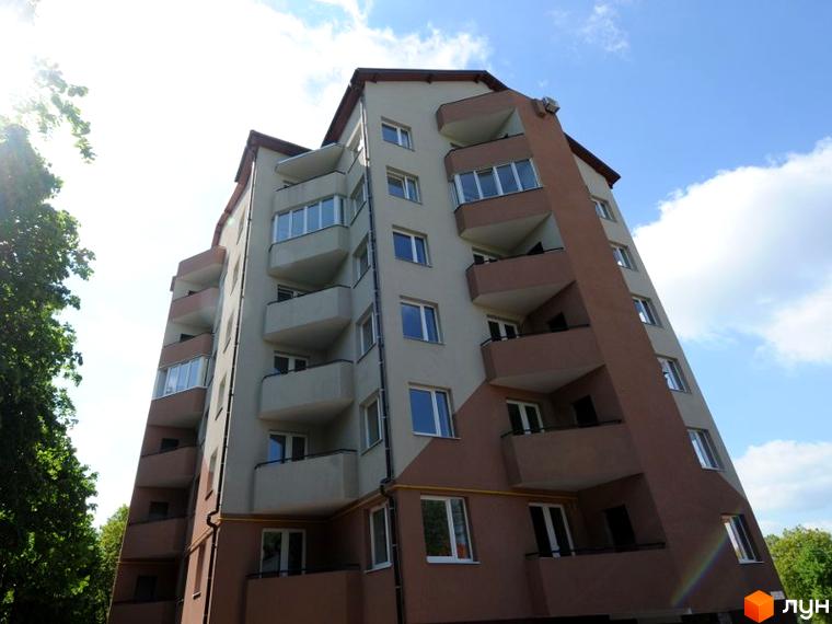 Фасад житлового комплексу на вул. Чорнобаївська (Чуваська), 29. Багатоповерховий будинок з балконами та вікнами на тлі блакитного неба з хмарами та зеленню дерев.