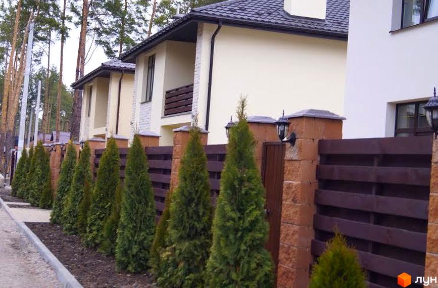 Зовнішній вигляд будинків житлового комплексу КМ Твій Дім з парканом та туями. Фото новобудови з фасадом та прибудинковою територією.
