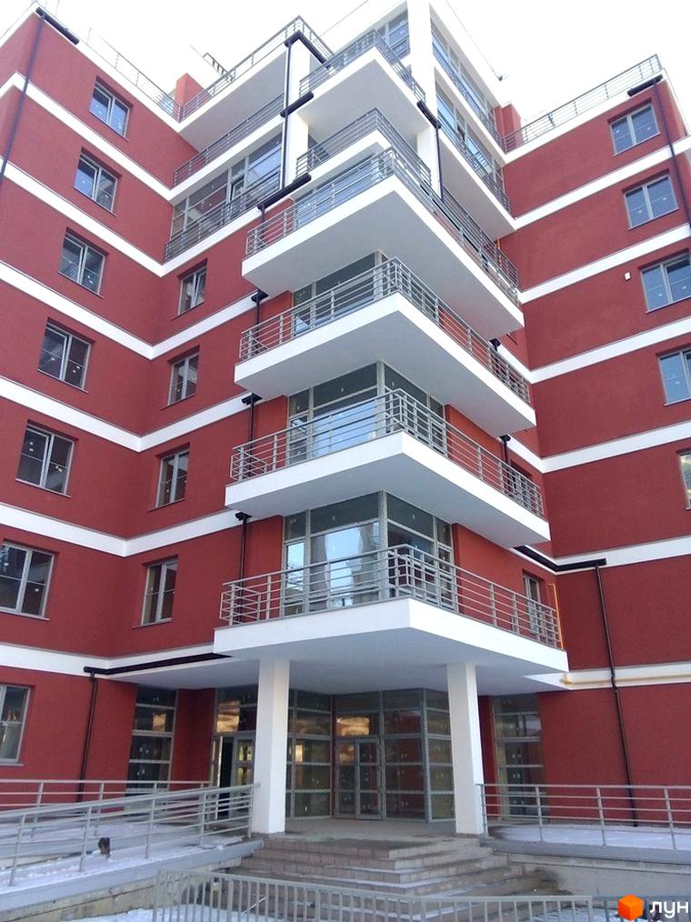 Зображення фасаду Новобудови Золотий горіх з балконами та вікнами. На фото видно частину прибудинкової території.