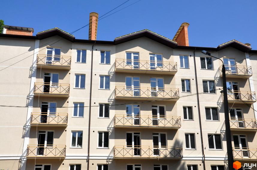 Зовнішній вигляд фасаду житлового комплексу Сосновий з балконами та вікнами. Будинок має кілька поверхів та цегляні димоходи.