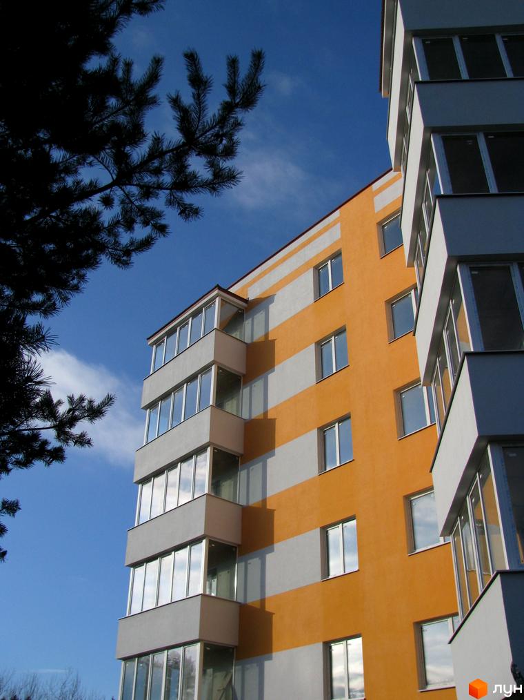 Висотна будівля з панорамним склінням на тлі блакитного неба. ЖК Приозерний пропонує комфортне житло з сучасним дизайном та зручним розташуванням.