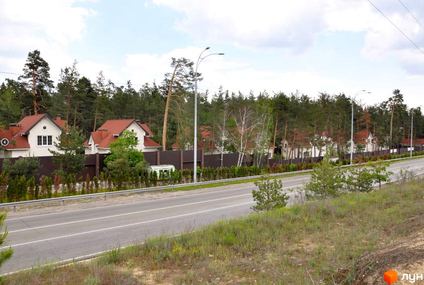 Зображення будинків з червоними дахами в Житловому комплексі AlpenPark. На передньому плані дорога та зелена прибудинкова територія.