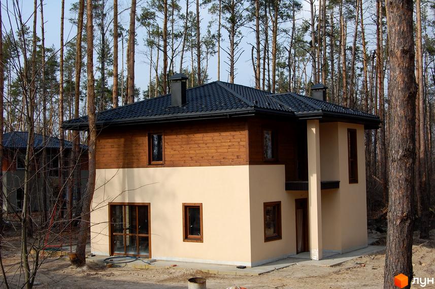 Котеджне містечко КМ Forest Family Avenue. Двоповерховий будинок з дерев'яним фасадом та світлими стінами, розташований серед високих сосен.
