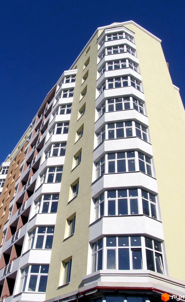 Зображення фасаду житлового будинку на вул. Варшавській, 193. Багатоповерхова будівля з великими вікнами та балконами на тлі блакитного неба.