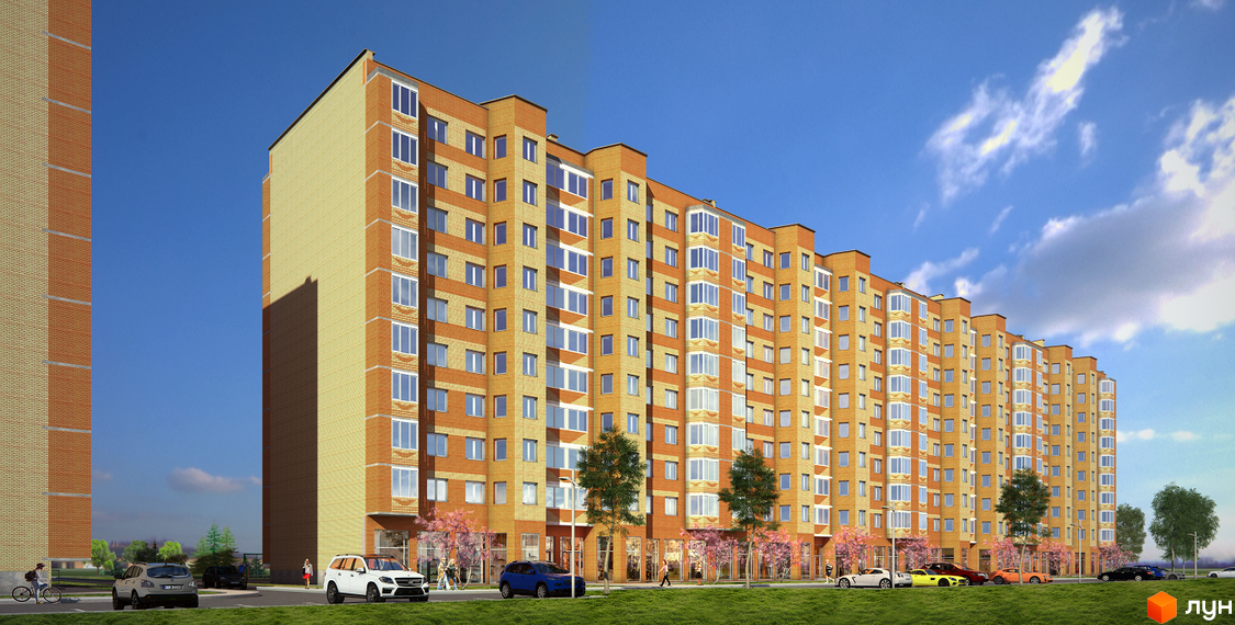 Житловий комплекс Spring Town: багатосекційний будинок з жовто-помаранчевим цегляним фасадом та вікнами. Перед ним зелений газон, дерева та припарковані авто.