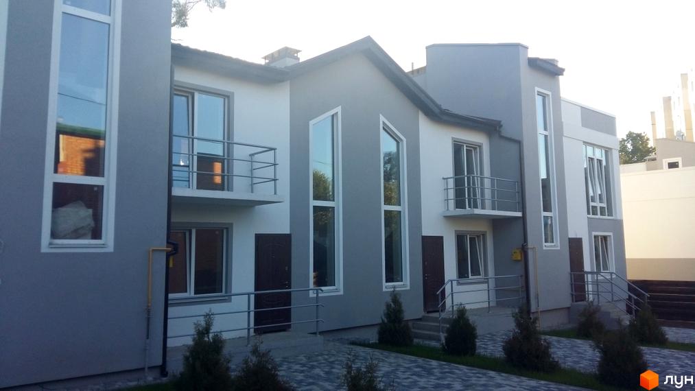 Зображення таунхаусів Таунхаус Емірати з сіро-білим фасадом, великими вікнами та балконами. Перед будинками брукована доріжка та зелені насадження.