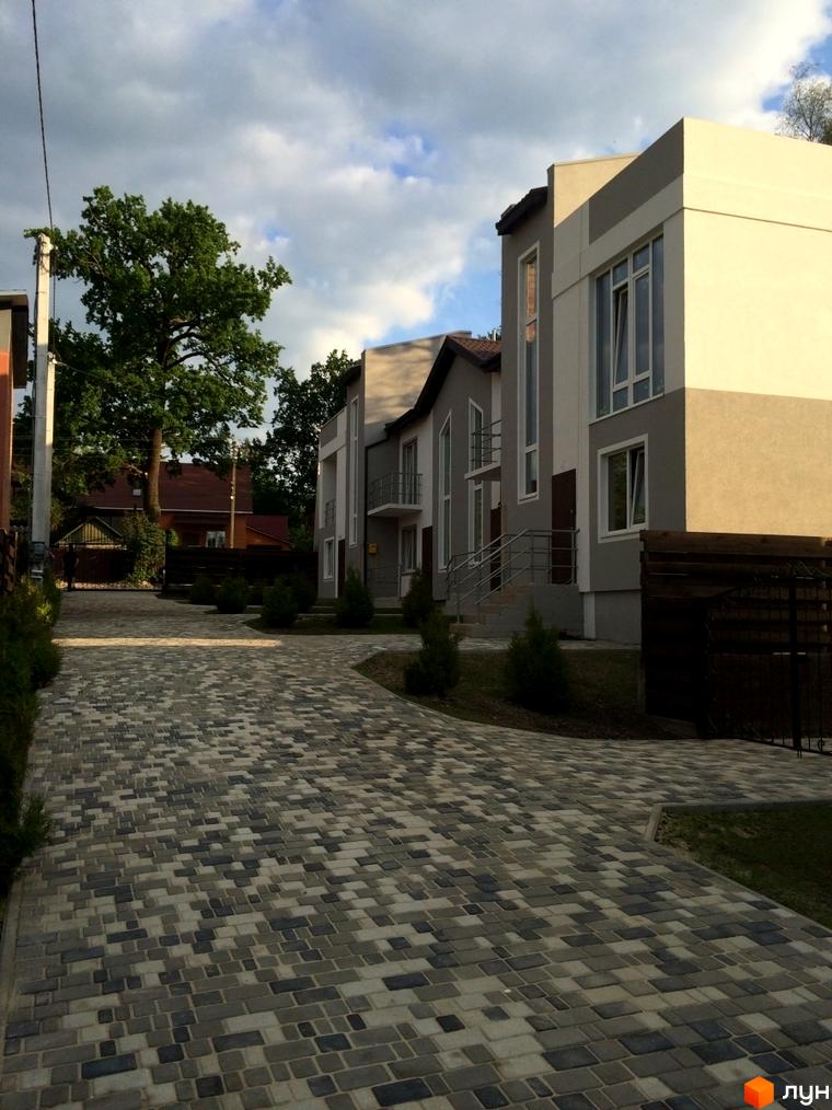 Таунхаус Емірати: будинки з комбінованими світлими та сірими фасадами, великими вікнами. Дорога викладена бруківкою, прибудинкова територія озеленена.