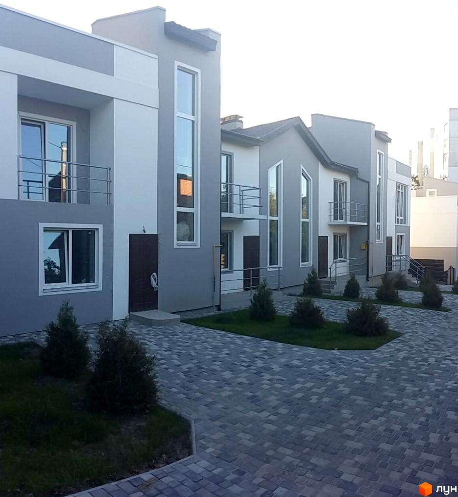 Ряд таунхаусів „Емірати“ з сіро-білими фасадами, великими вікнами та балконами. Прибудинкова територія викладена бруківкою, є зелені насадження.