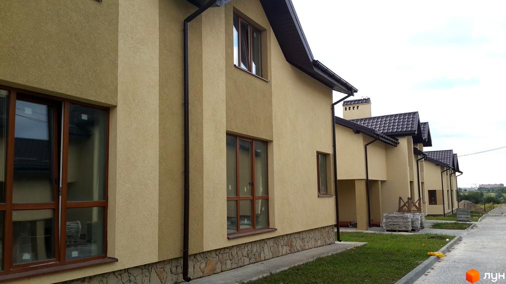 Ряд бежевих будинків з коричневими дахами та вікнами, облицьованих каменем знизу, на вул. Бічна Івана Франка, 35-37. Перед будинками зелений газон та вимощені доріжки.