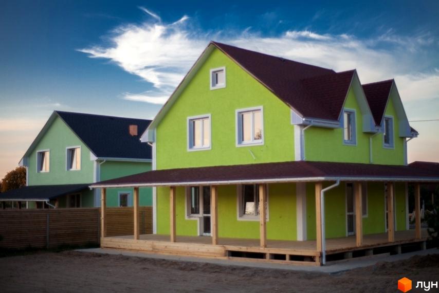 Котеджне містечко HappyTown: будинок салатового кольору з темно-червоним дахом та дерев'яною верандою. На передньому плані ґрунтова ділянка.