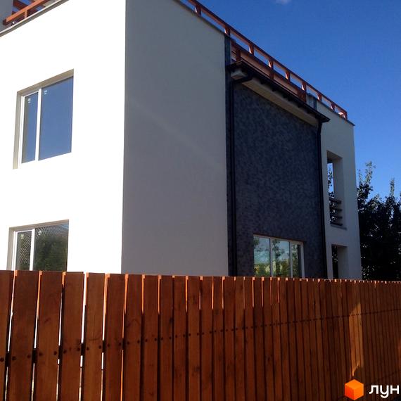 Зовнішній вигляд Котеджне містечко High-Tech House: білий будинок з темною фасадною обробкою та дерев'яним парканом.