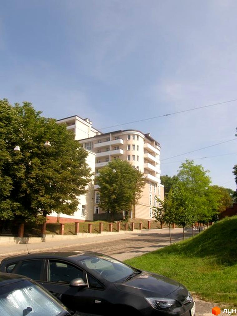 Зображення будинку по вулиці Мечникова, 16а. Багатоповерхова новобудова з балконами, поруч дерева та припарковані автомобілі.