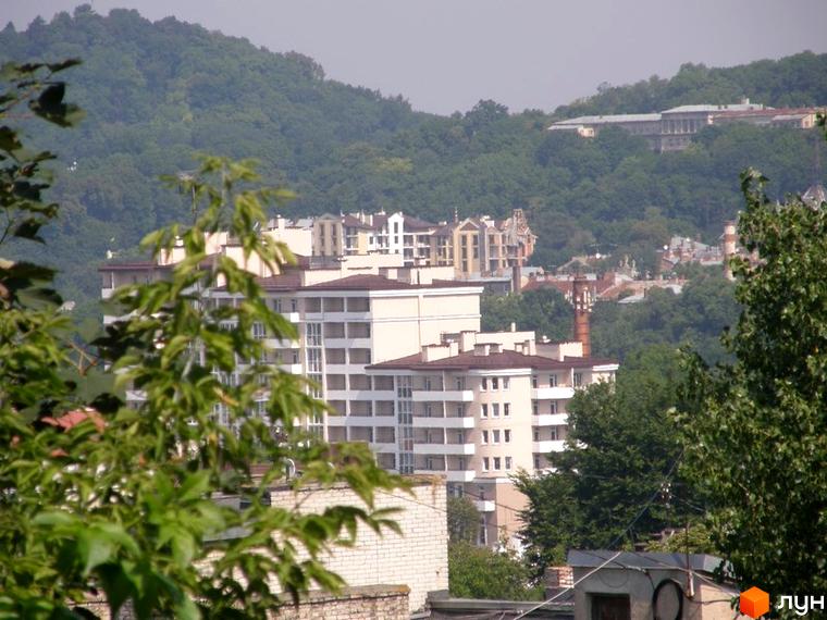 Фото багатоповерхового будинку на вулиці Мечникова, 16а. Вигляд на фасад новобудови та зелені насадження навколо.