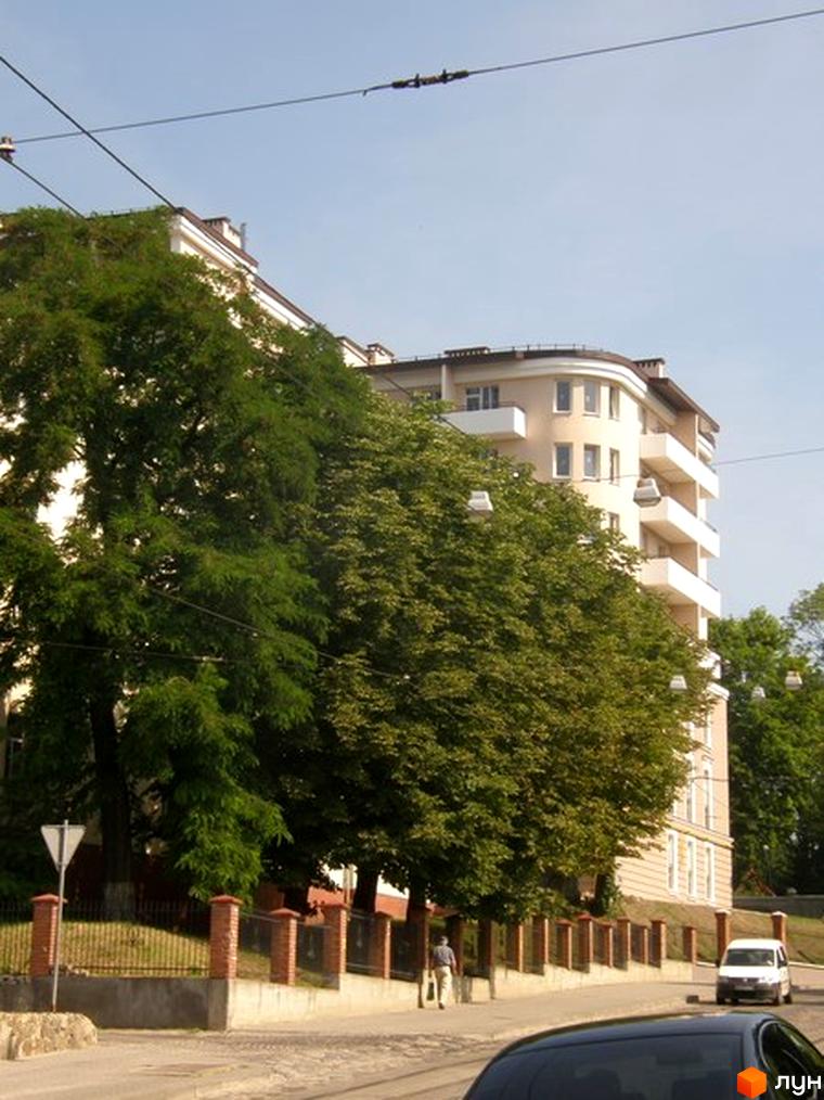 Зовнішній вигляд будинку на вул. Мечникова, 16а. Багатоповерхова будівля з балконами, оточена зеленими насадженнями та пішохідною зоною.