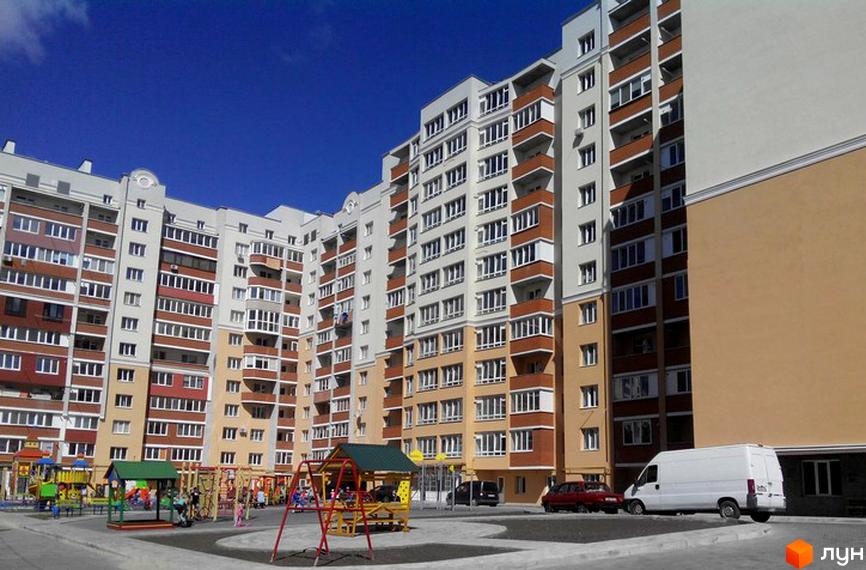 Фото фасаду багатоповерхового будинку на вулиці Лісогринівецька, 26/3, 28, 30/3, 30/4. На передньому плані дитячий майданчик з гойдалками та гірками.