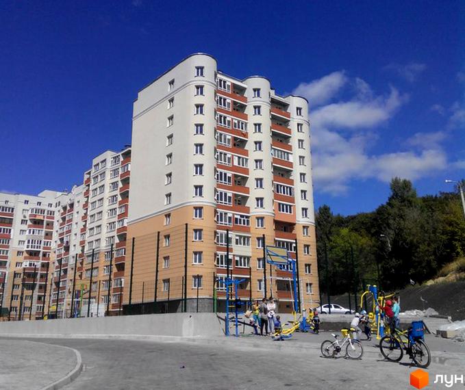 Зображення багатоповерхового будинку за адресою вул. Лісогринівецька, 26/3, 28, 30/3, 30/4. На передньому плані дитячий майданчик та велосипеди.