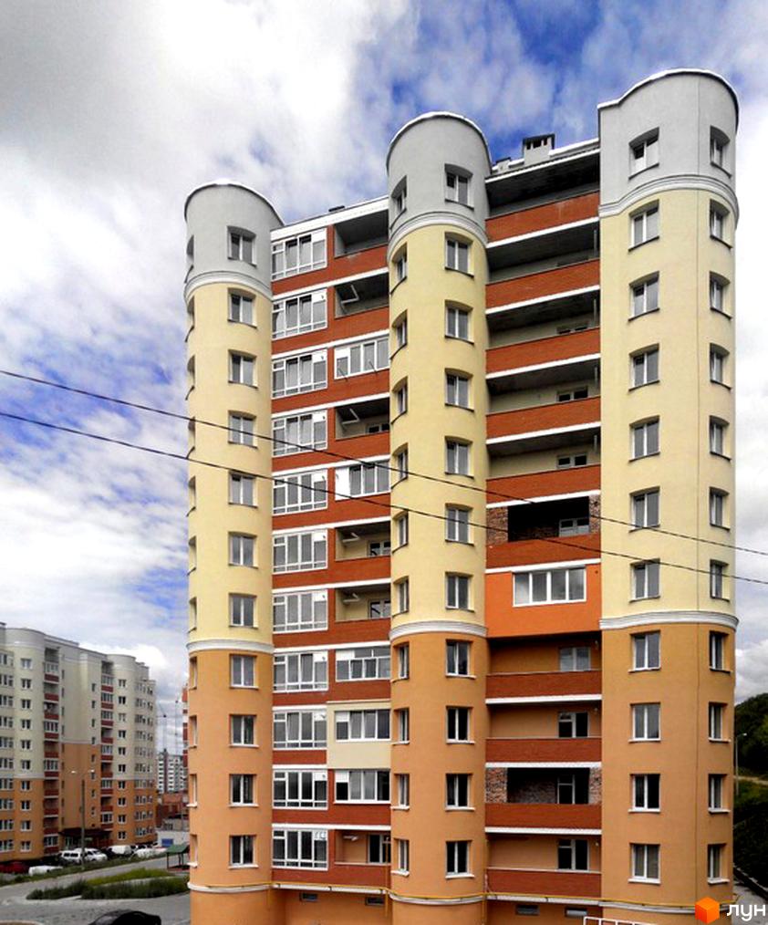 Зображення багатоповерхового будинку на вулиці Лісогринівецька. Архітектура з круглими вежами, фасади в жовтих та помаранчевих тонах, великі вікна.