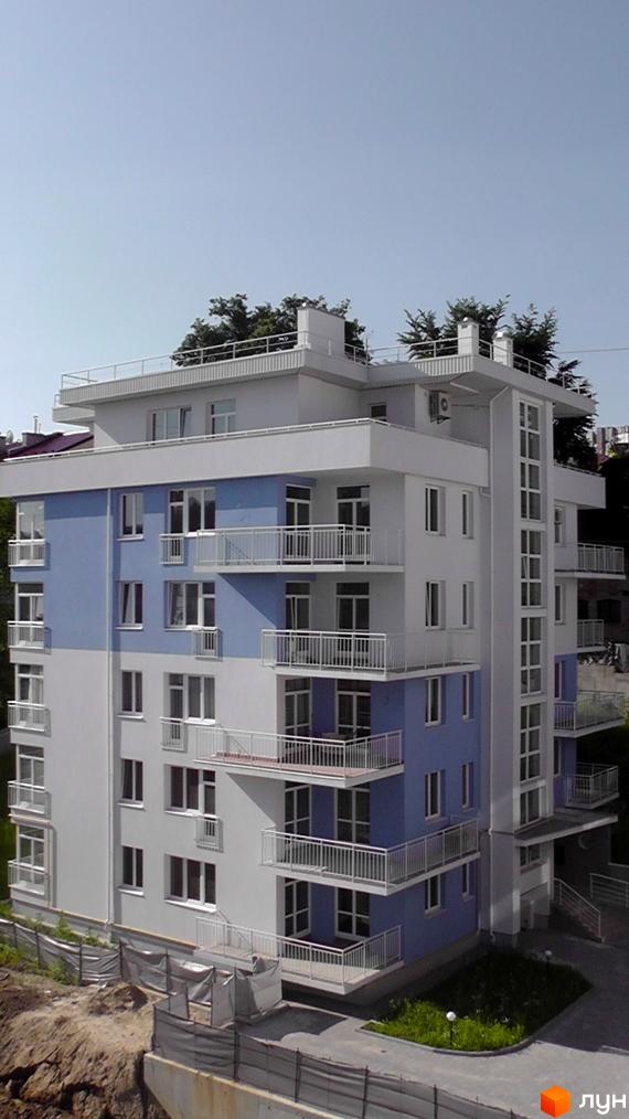 Зображення фасаду та балконів Житлового комплексу Оберіг. Багатоповерховий будинок з блакитними вставками та білими балконами.
