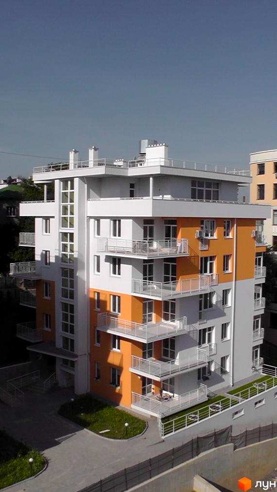 Фото фасаду та прибудинкової території Житлового комплексу Оберіг. Багатоповерхова будівля з балконами та газоном біля будинку.