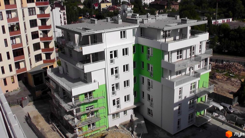 Зображення фасаду будинку в Житловому комплексі Оберіг. Багатоповерхівка з балконами та зеленими вставками на стінах.