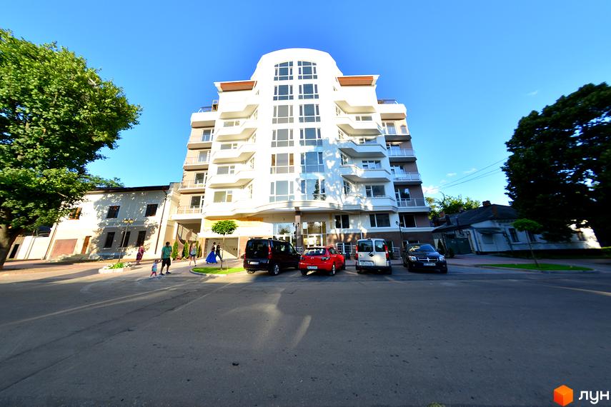 Новобудова на вулиці Мала Морська, 2а. Будинок білого кольору з балконами та великими вікнами. Поруч розташовані дерева та припарковані автомобілі.