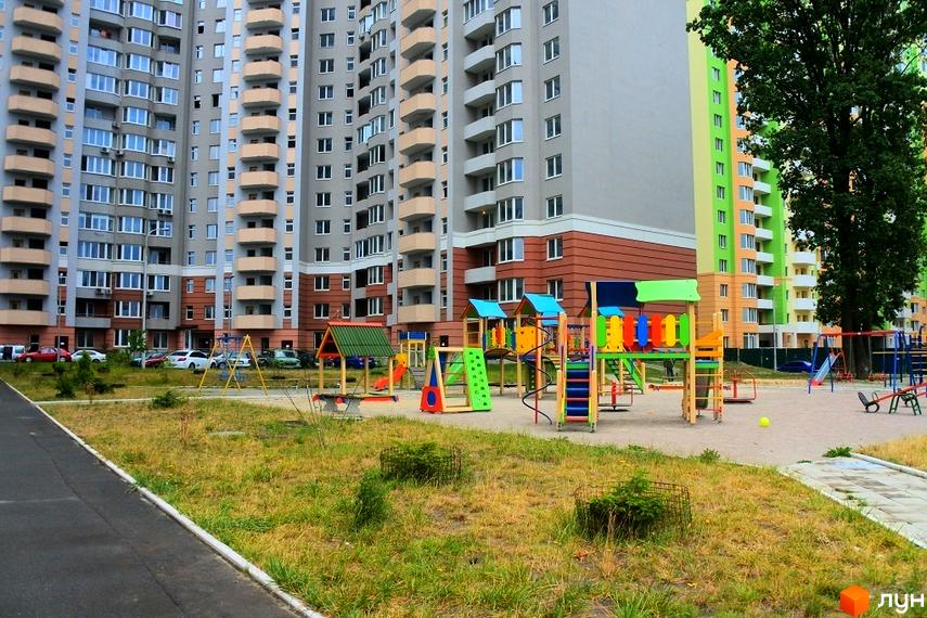 Житловий комплекс Коцюбинський: багатоповерхові будинки з балконами та яскравий дитячий майданчик на прибудинковій території.
