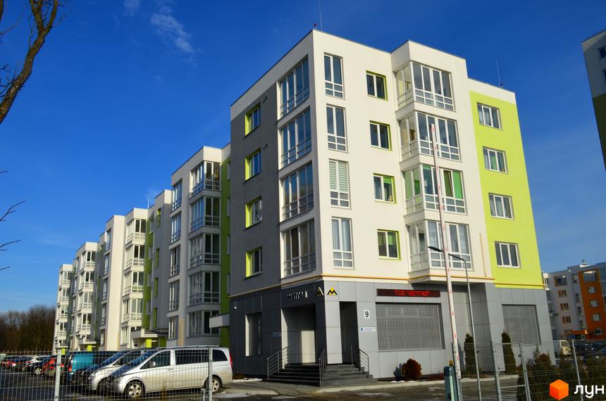 Зовнішній вигляд Житлового комплексу Новий: багатоповерховий будинок з великими вікнами та балконами. На передньому плані парковка з автомобілями.