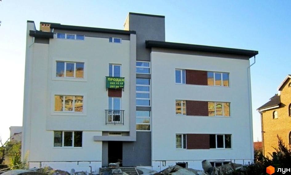 Зовнішній вигляд триповерхового будинку на вул. Стрийській, 254. Світлий фасад з великими вікнами та балконом, прибудинкова територія з будівельним сміттям.
