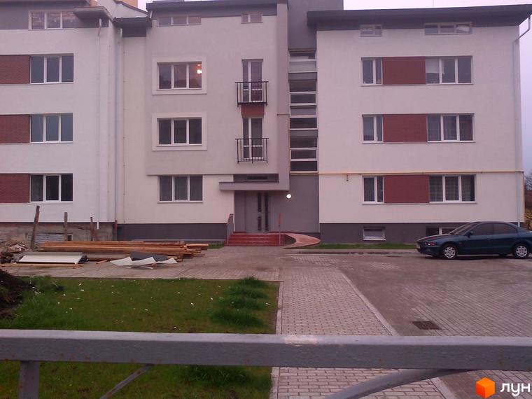 Зовнішній вигляд житлового будинку по вулиці Стрийська, 254. На передньому плані прибудинкова територія з тротуаром та газоном.