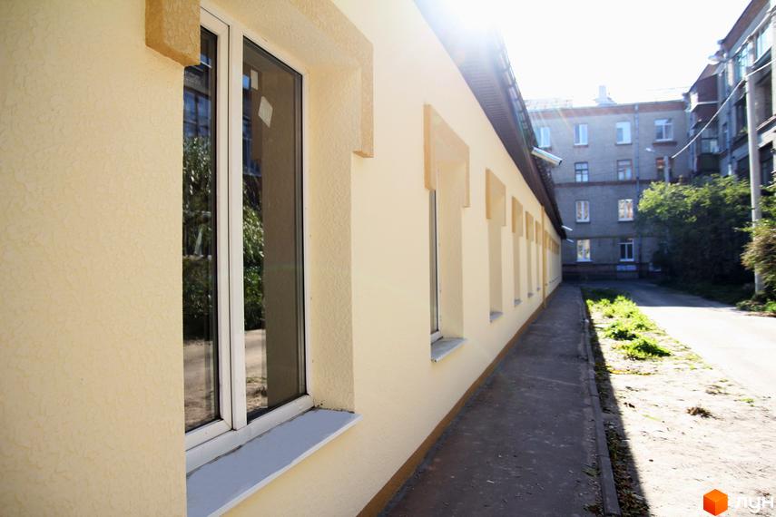 Зовнішній вигляд новобудови ЖБ Етюд з вікнами та оздобленням фасаду. Прибудинкова територія з алеєю та сусідніми будинками.