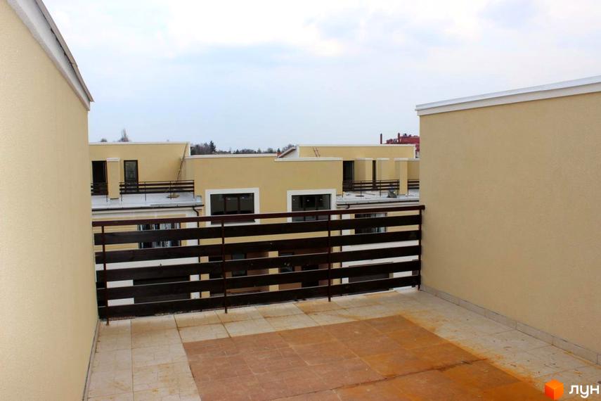 Зовнішній вигляд новобудови на вул. Кибалюка, 17. Тераса з дерев'яною огорожею та плиткою на підлозі.