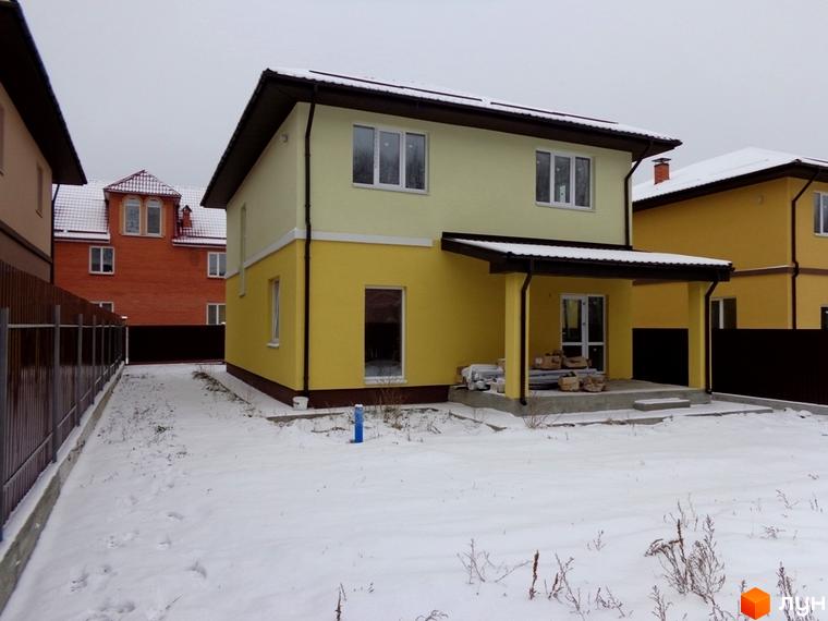 Фото будинку в Котеджному містечку Village-Мархалівка. Двоповерховий будинок з жовтим фасадом та коричневим дахом, сніг на подвір'ї.