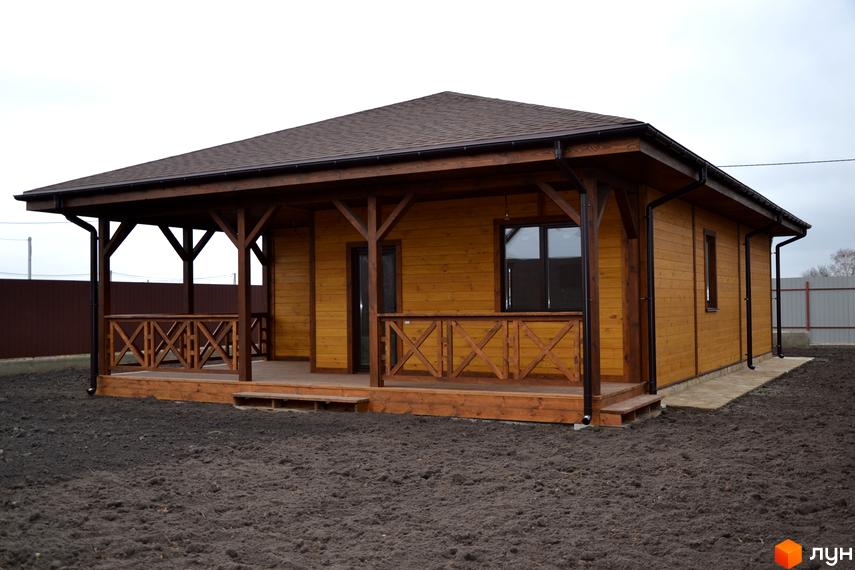 Одноповерховий будинок з дерев'яним оздобленням та терасою. Навколо будинку знаходиться ділянка з землею.