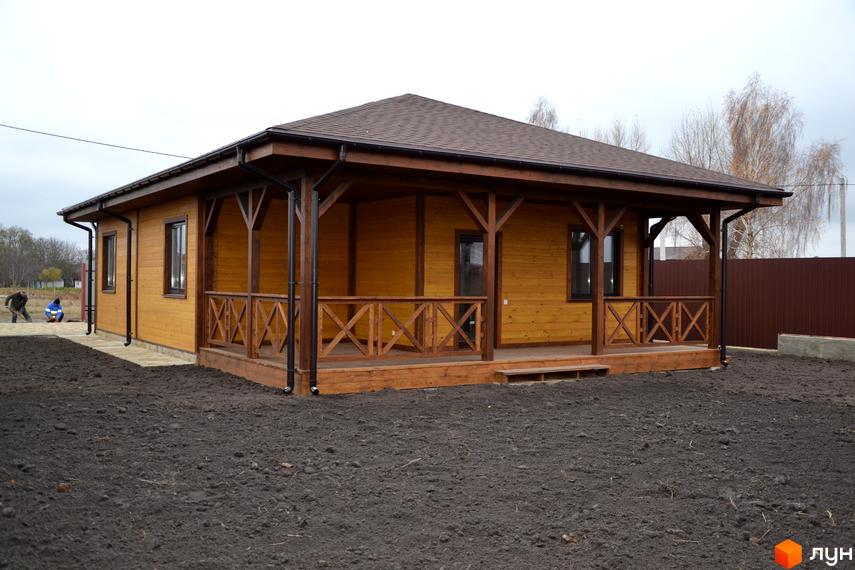 Одноповерховий будинок з дерев'яним фасадом та терасою. Навколо будинку знаходиться прибудинкова територія з землею.