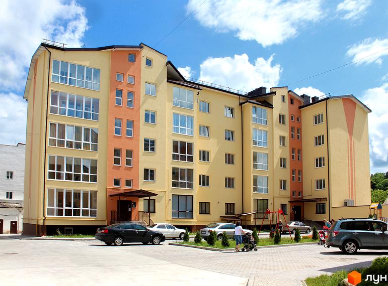 Зображення фасаду будинку по вул. Юрія Руфа (Некрасова), 36. Житловий комплекс з жовтими стінами та великими вікнами, на подвір'ї автомобілі та дитячий майданчик.