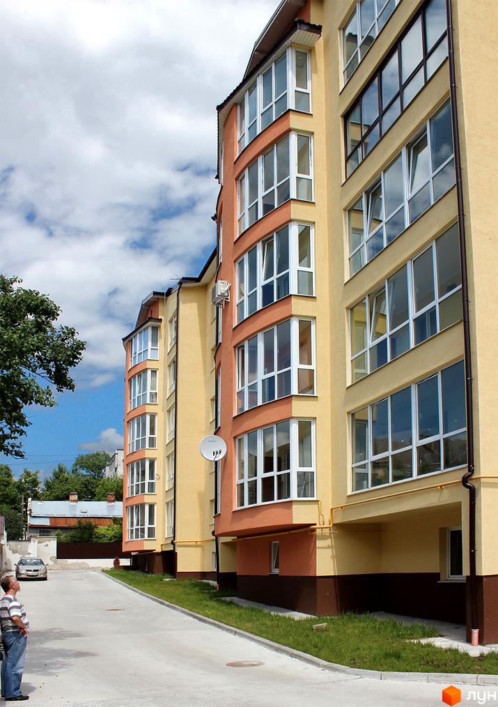 Зображення фасаду будинку на вулиці Юрія Руфа (Некрасова), 36. Багатоповерхова будівля з великими вікнами та балконами, поруч тротуар та зелена зона.