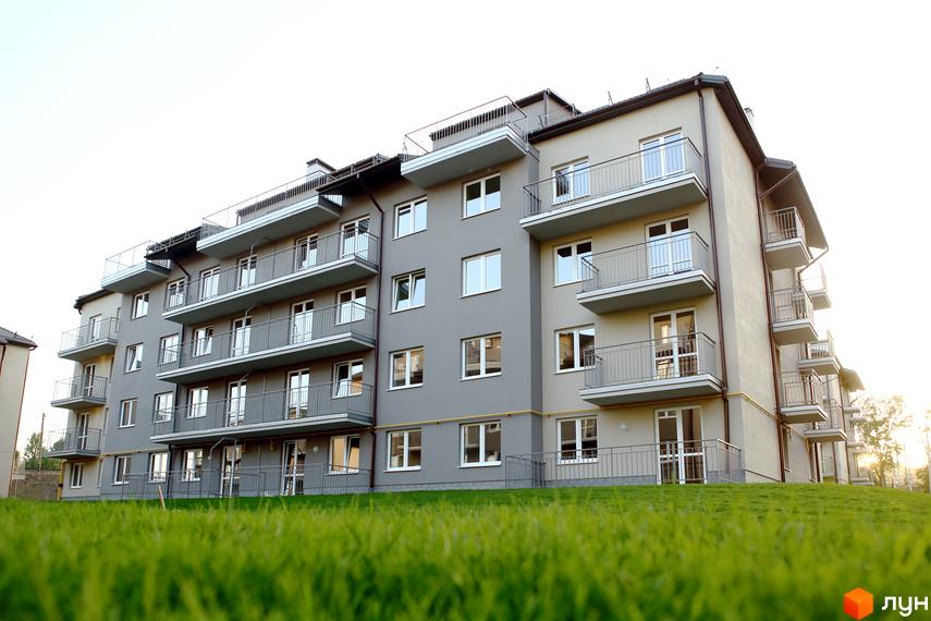 Зображення багатоповерхового будинку з балконами в Житловому комплексі Бельгійське містечко. Зелений газон перед будинком.