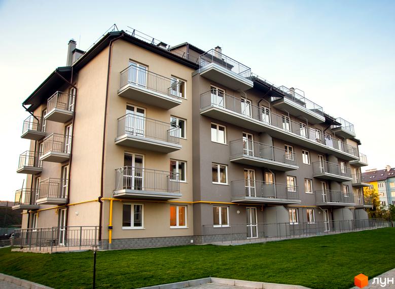 Зображення фасаду будинку в Житловому комплексі Бельгійське містечко. Багатоповерхова будівля з балконами та зеленою прибудинковою територією.