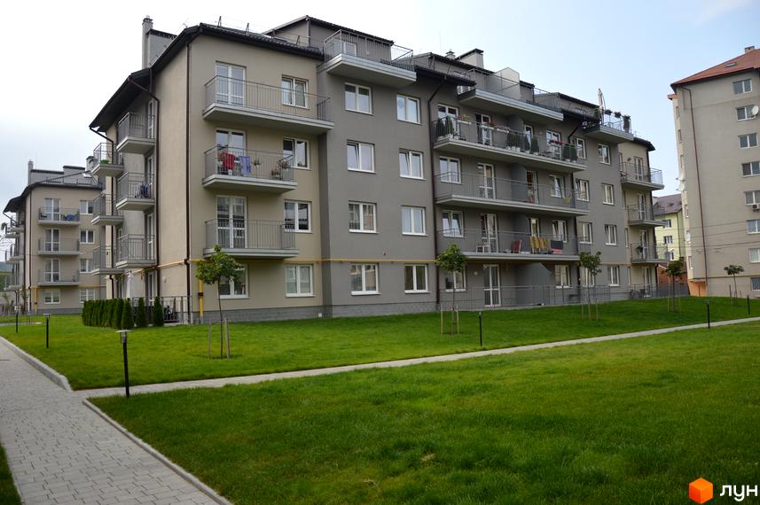 Зображення багатоквартирного будинку в Житловому комплексі Бельгійське містечко. На фото видно фасад будівлі та зелену прибудинкову територію.