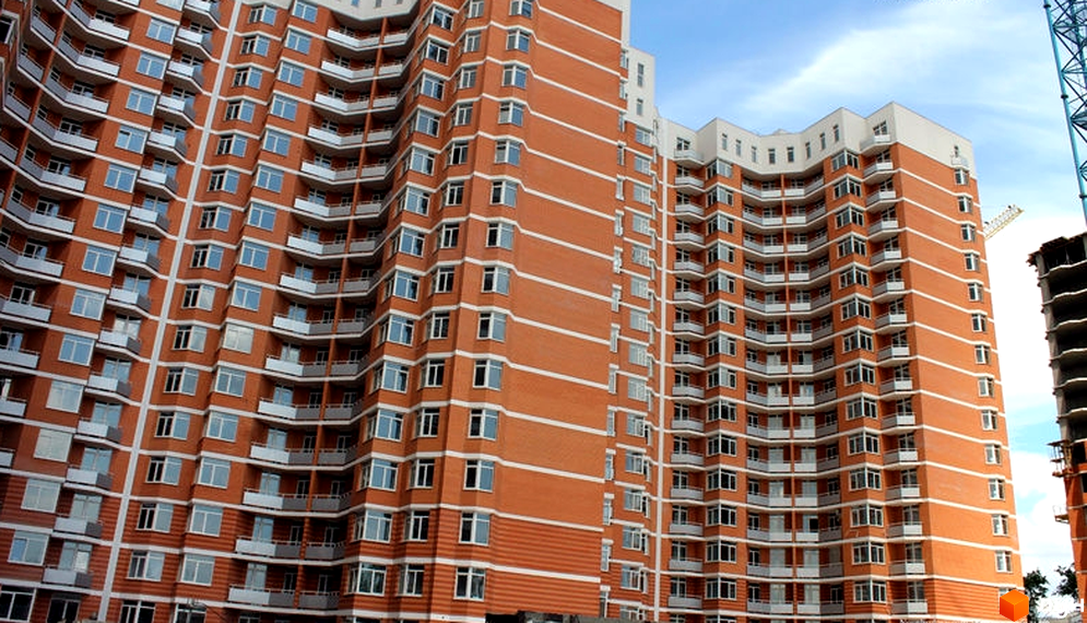 Житловий комплекс Романівський: високі будинки з цегляними фасадами, численними вікнами та білими балконами під блакитним небом.