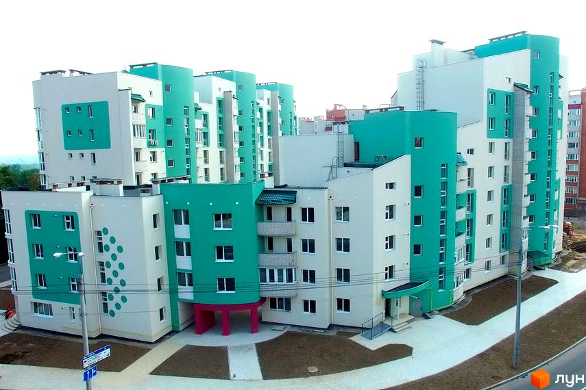 Житловий комплекс Мікрорайон „Поділля“ з яскравими фасадами та прибудинковою територією, облаштованою пішохідними доріжками.