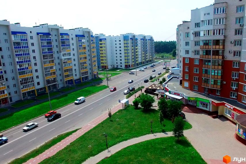 Житловий комплекс Мікрорайон „Поділля“ з сучасними будинками та зеленою прибудинковою територією. Вид на дороги та автомобілі поблизу.